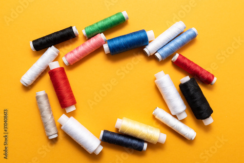 colored sewing threads on yellow background