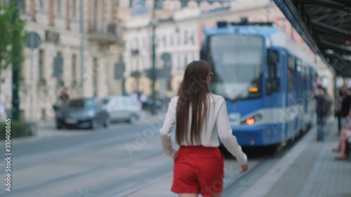 female city dweller is walking on tram station in city