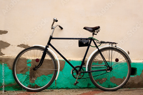 Old fashioned bicycle near rural pale yellow stucco wall © nathings
