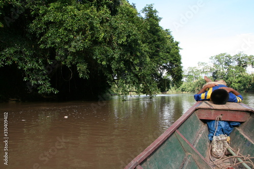 niño descansando en la proa de una barca por el amazonas