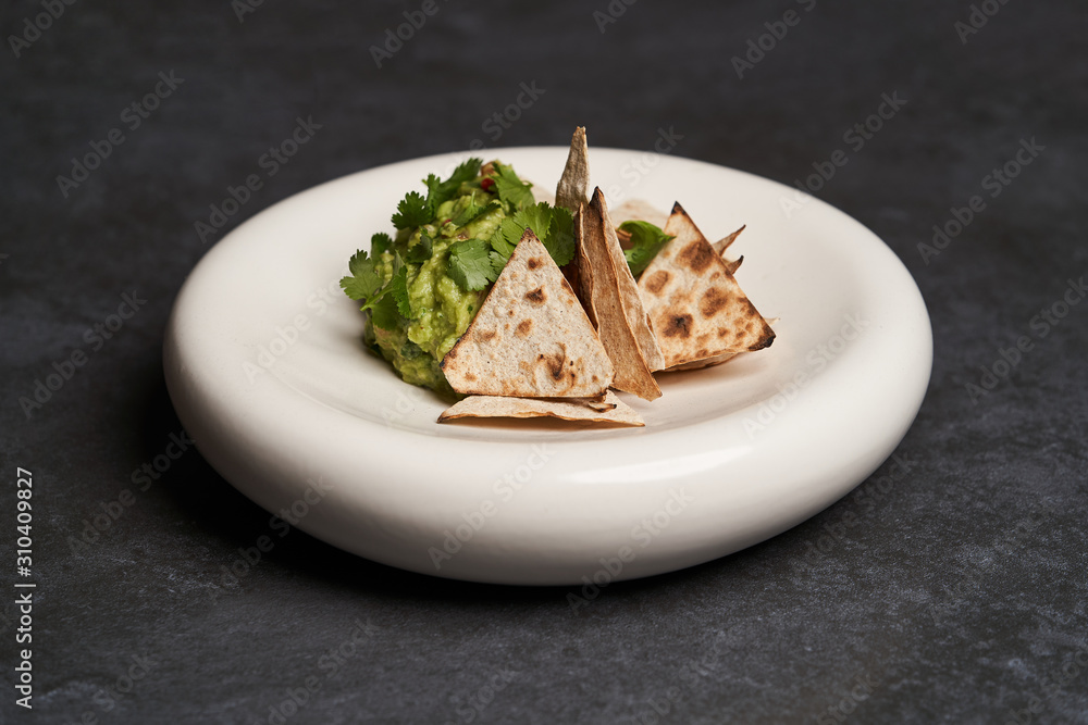 Guacamole with pita chips on white plate. Chef's signature dish Guacamole with pita chips on white plate. Chef's signature dish