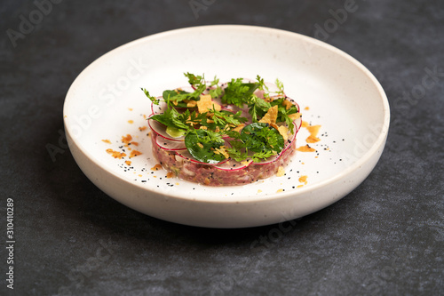 Fototapeta Naklejka Na Ścianę i Meble -  Fresh beef tartare dish with fresh vegetables in white plate