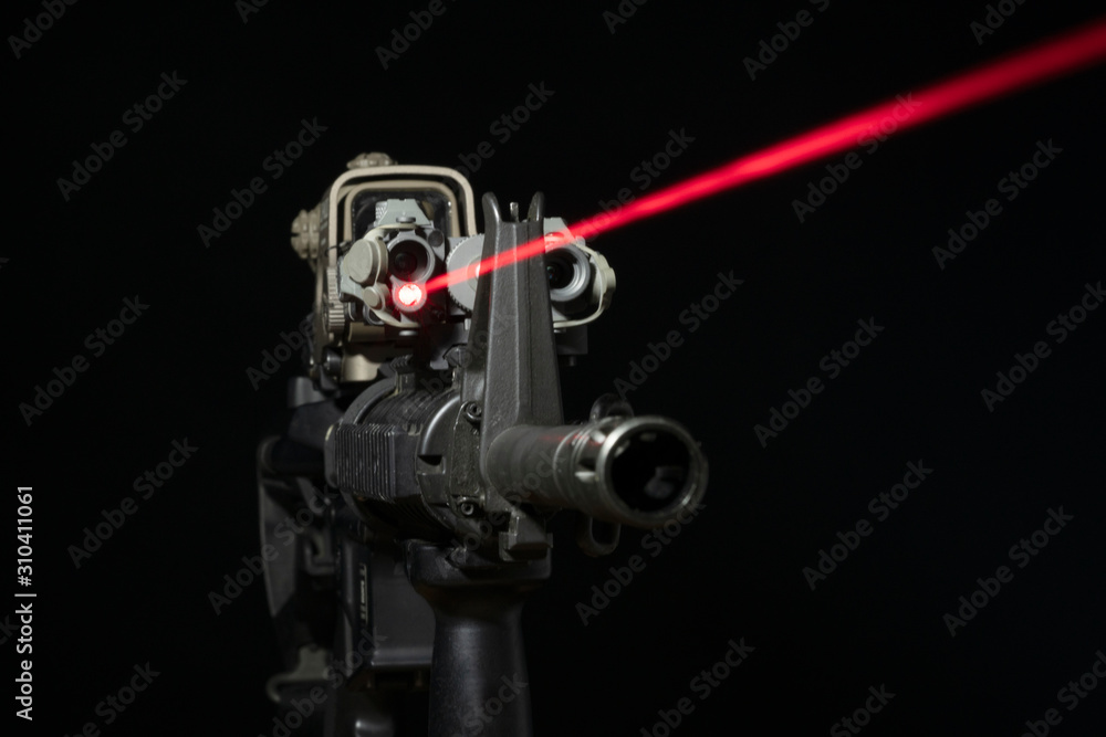 Optical sight and laser device with a red beam on the M4 rifle on dark background Optical sight and laser device with a red beam on the M4 rifle on dark background