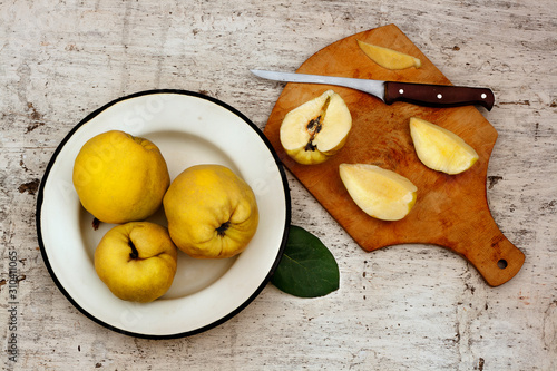 Rural still life ripe yellow quince fruits on the plate and cut fruit on plate with knife photo