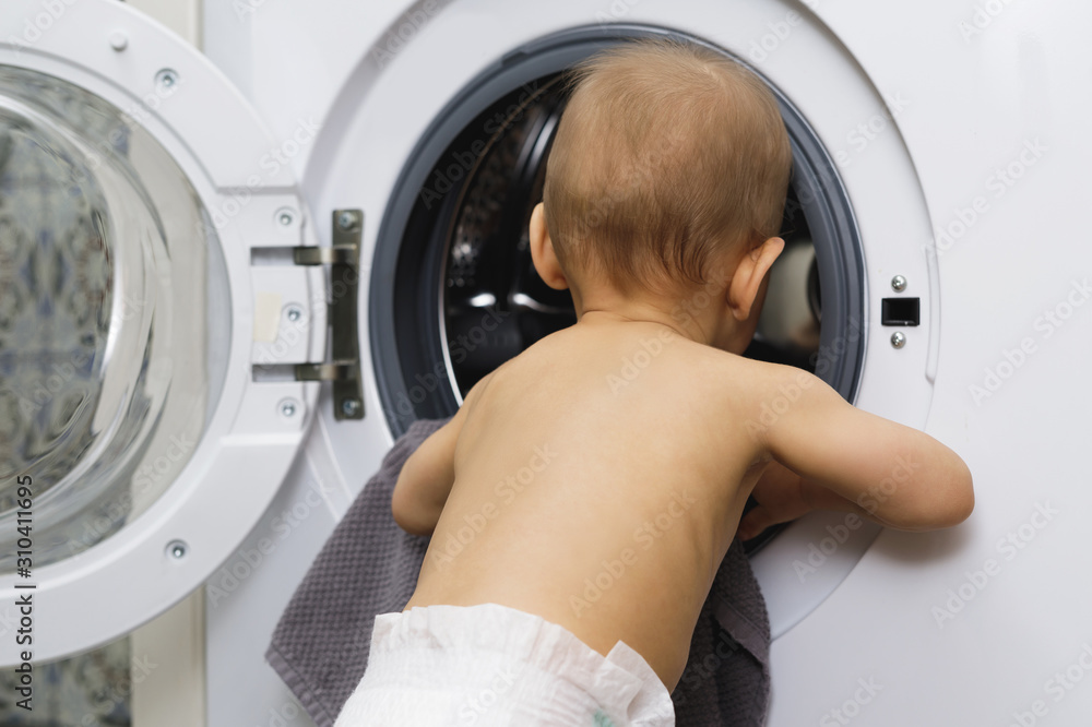 Cute baby boy is looking inside the washing machine Cute baby boy is looking inside the washing machine