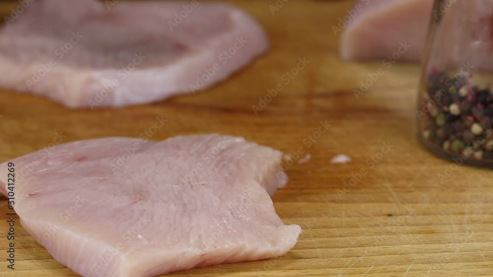 Woman beats turkey steaks with a kitchen hammer, close-up Woman beats turkey steaks with a kitchen hammer, close-up