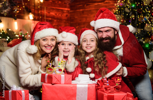 Little Christmas magic. merry christmas. Father and mother love kids. lot of xmas present boxes. small children and parents in santa hat. Portrait loving family. Happy family celebrate new year