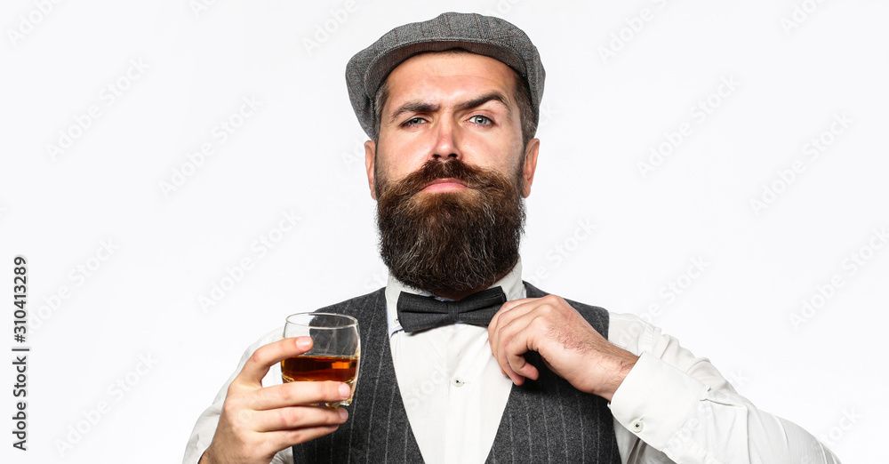 Bearded man wearing suit and drinking whiskey, brandy, cognac. Bearded in is holding a glass of whiskey Bearded man wearing suit and drinking whiskey, brandy, cognac. Bearded in is holding a glass of whiskey