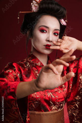 Image of young geisha woman in traditional japanese kimono dancing photo