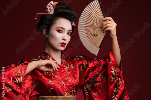 Fotografia Image of young geisha woman in japanese kimono holding wooden hand fan