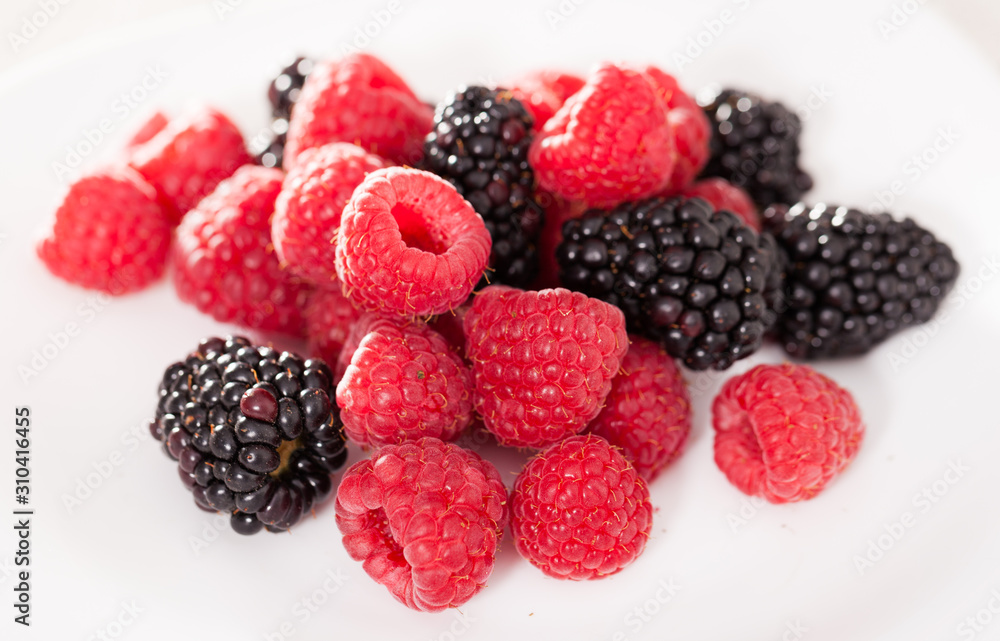 handful of raspberry and blackberry berries on white background handful of raspberry and blackberry berries on white background