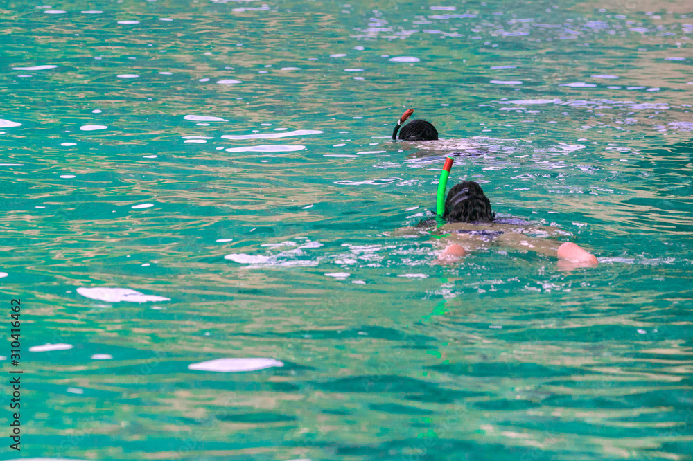 Two snorkelers swim in clear turquoise water.