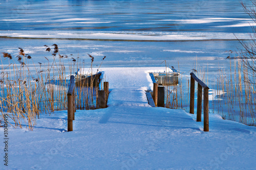 Steg mit Schnee über einem zugefrorenen Bergsee photo