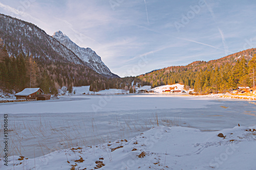 Zugefrorener Bergsee mit steiler Felswand im Hintergrund photo