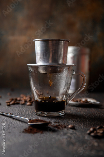 Fotografía Preparation of Vietnamese coffe with aluminum cofe filer on dark background