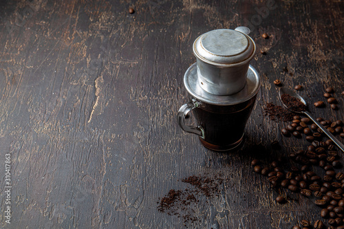 Fotografía Preparation of Vietnamese coffe with aluminum cofe filer on dark background