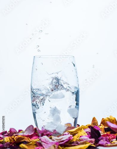 falling ice cube into a water glass making bubbles with a with background  photo