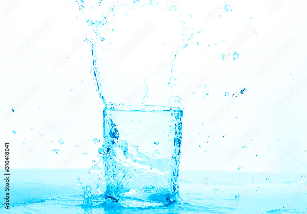 water splashing into a empty water glass, where the pured water is making splash, drops and shapes