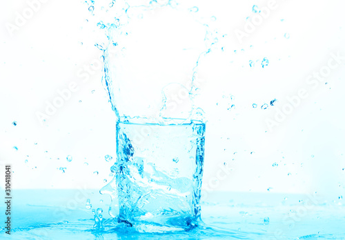 water splashing into a empty water glass, where the pured water is making splash, drops and shapes