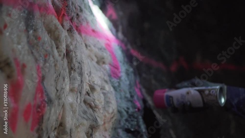 Underground person spraying pink paint onto gold bearing rock face photo