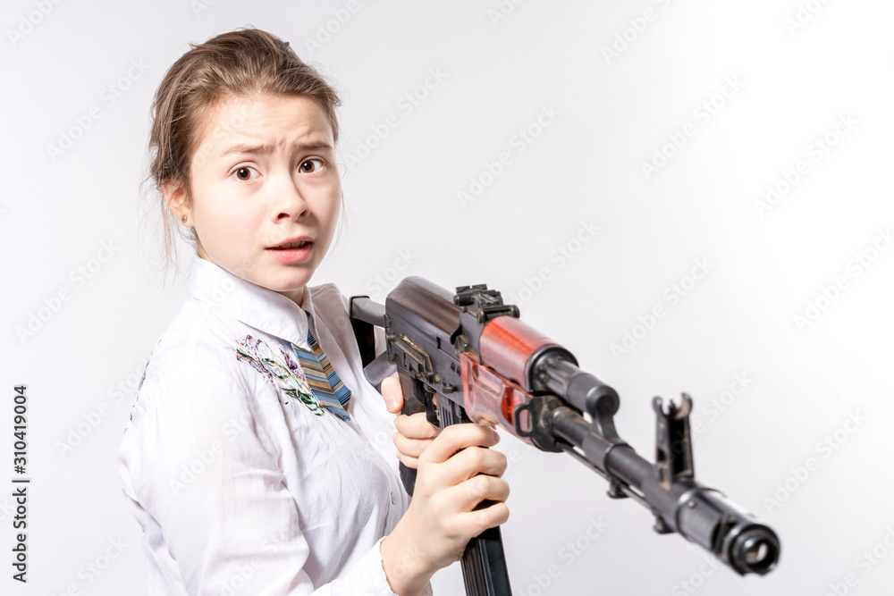 Girl with a frightened look with a Kalashnikov assault rifle in her hands on a white background in the studio. Girl with a frightened look with a Kalashnikov assault rifle in her hands on a white background in the studio.