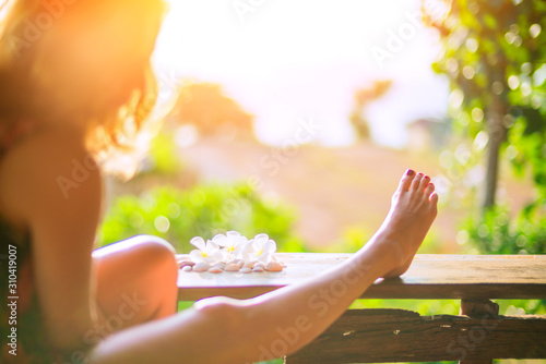 The girl sitting on a wooden porch in a summer sunny day.