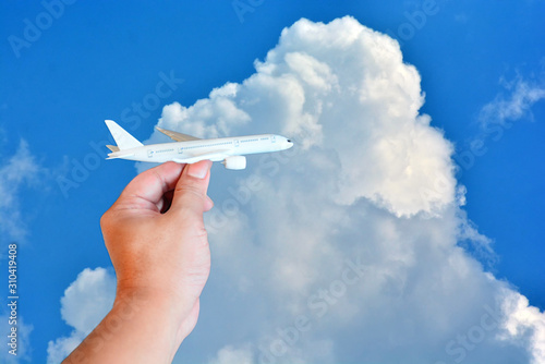 toy airplane in hand on beautiful sky with cloud background in concept travel around the world