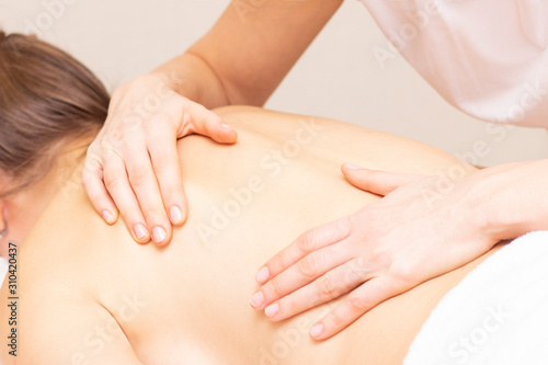 Massage and body care. Spa woman body massage with hands treatment. Stretching the back muscles. Woman having massage at the spa for beautiful girl