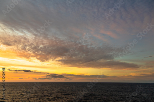 Sunset and dramatic set of clouds drifting over the tropical waters of the Caribbean Sea are lit by the last moments of daylight