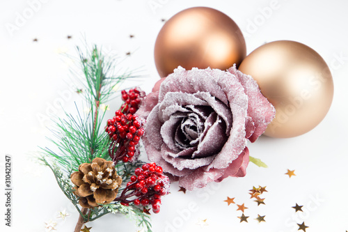 Christmas tree branch with berries snow with pink rose and two golden balls and little golden stars