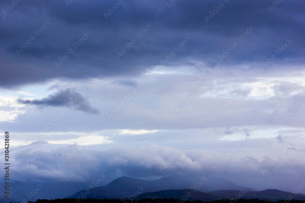 View of heavy rain falling on the Snowdonia Mountain range from the Isle of Anglesey