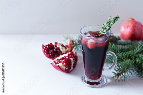 Pomegranate Christmas cocktail with champagne, soda and rosemary on a white table. Xmas drink.