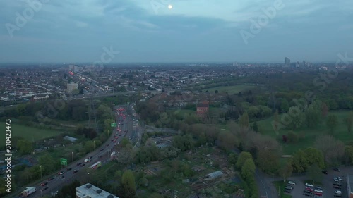 Moon in a cool blue sky at dusk over busy A12 road in Wanstead, London.  Drone rising, tilt forward. photo