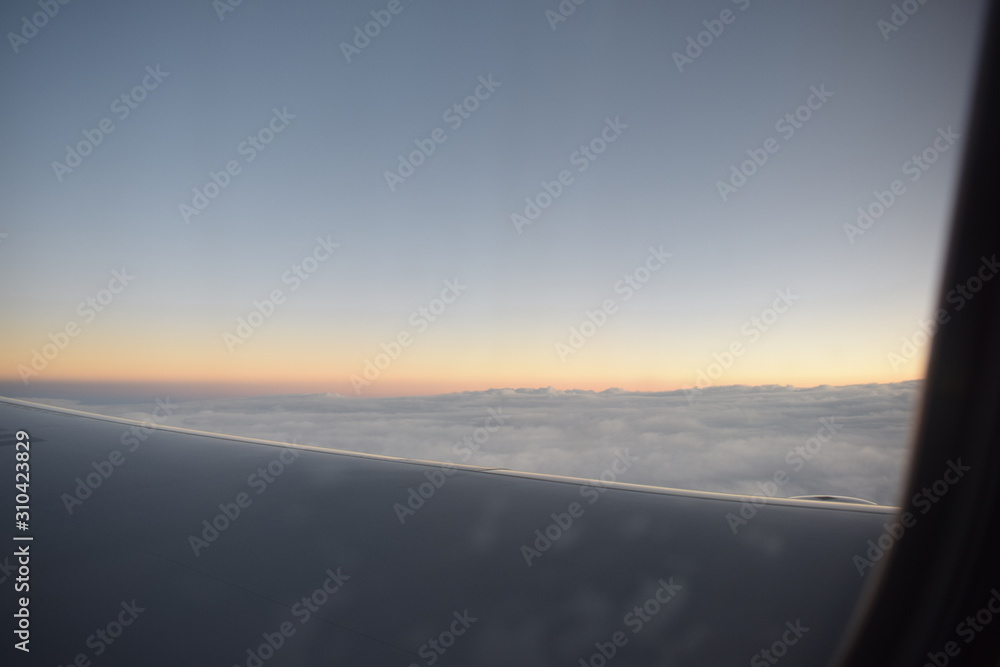 Wing of an airplane flying above the clouds. people look at the sky from the window of the plane, using air transport to travel. back light sun beam