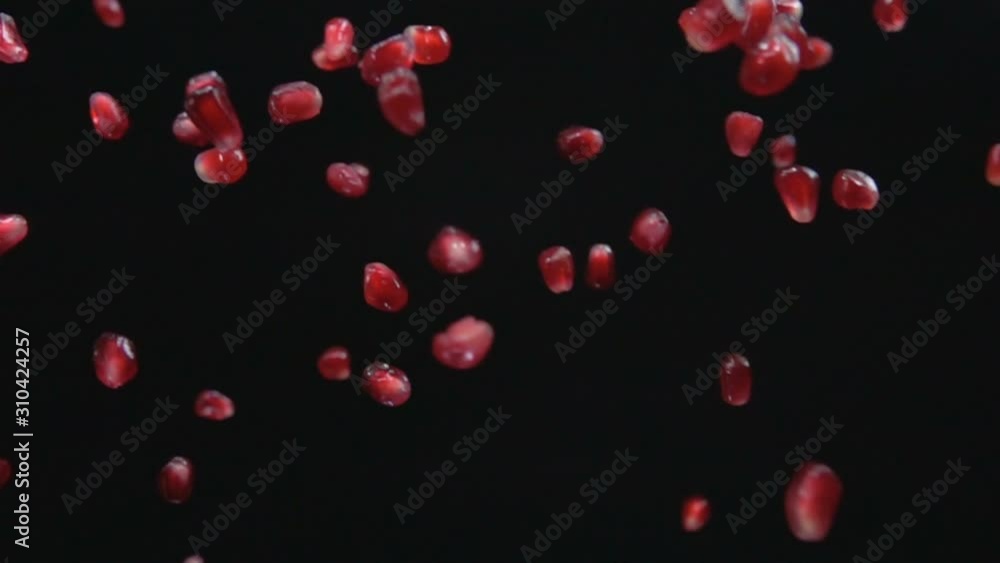 Juicy grains of ripe pomegranate are falling on the black background Juicy grains of ripe pomegranate are falling on the black background