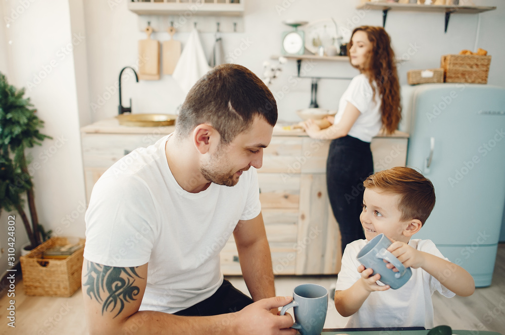 Family in a kitchen. Beautiful mother in a white t-shirt. Cute little boy Family in a kitchen. Beautiful mother in a white t-shirt. Cute little boy