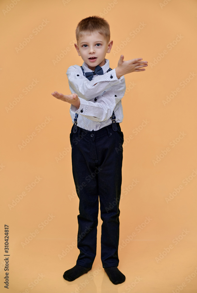 Portrait of a cute 10 years old schoolboy boy on a beige background. Standing straight at full height, Showing emotions, talking. Portrait of a cute 10 years old schoolboy boy on a beige background. Standing straight at full height, Showing emotions, talking.