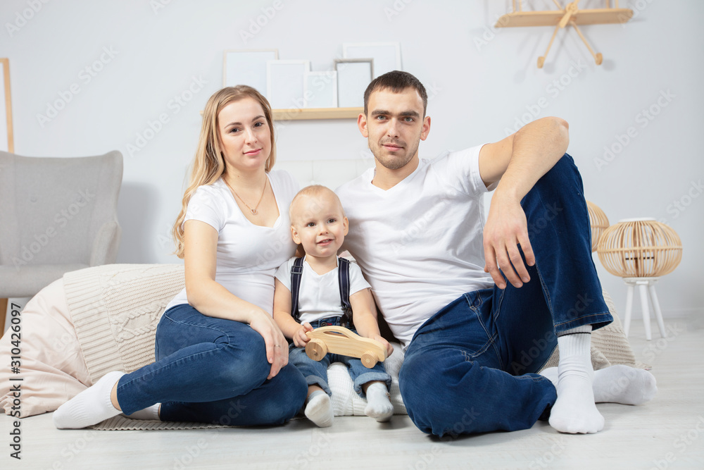 Family. Dad mom child sit on the floor at home. Portrait husband wife and little son. Couple with baby in the apartment Family. Dad mom child sit on the floor at home. Portrait husband wife and little son. Couple with baby in the apartment