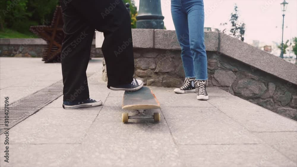 The guy is teaching his girlfriend to skateboard. Date of hipsters. The guy is teaching his girlfriend to skateboard. Date of hipsters.