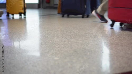 Arriving and departing people at a busy international airport, carry their luggage in their hands, pull their suitcases on wheels, some passengers use luggage trolleys. Tourists walk through the hall