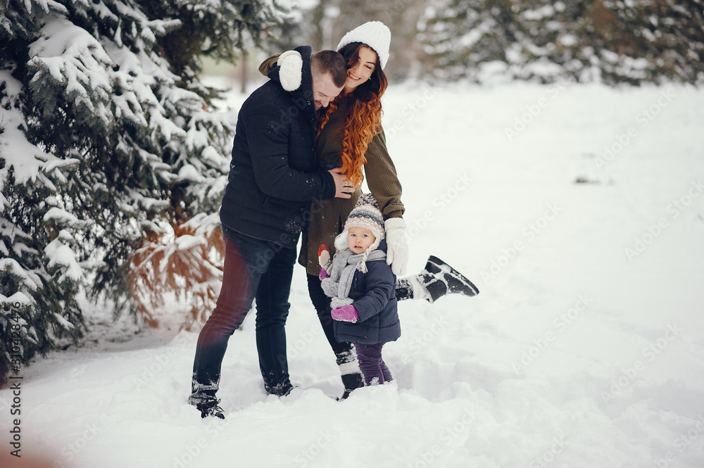Family have fun in a winter park. Stylish mother in a green sweater. Little girl in a winter clothes. Family have fun in a winter park. Stylish mother in a green sweater. Little girl in a winter clothes.