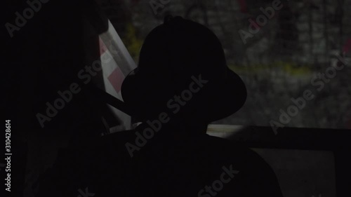 Silhouette of person wearing hard hat working underground operating heavy machinery photo