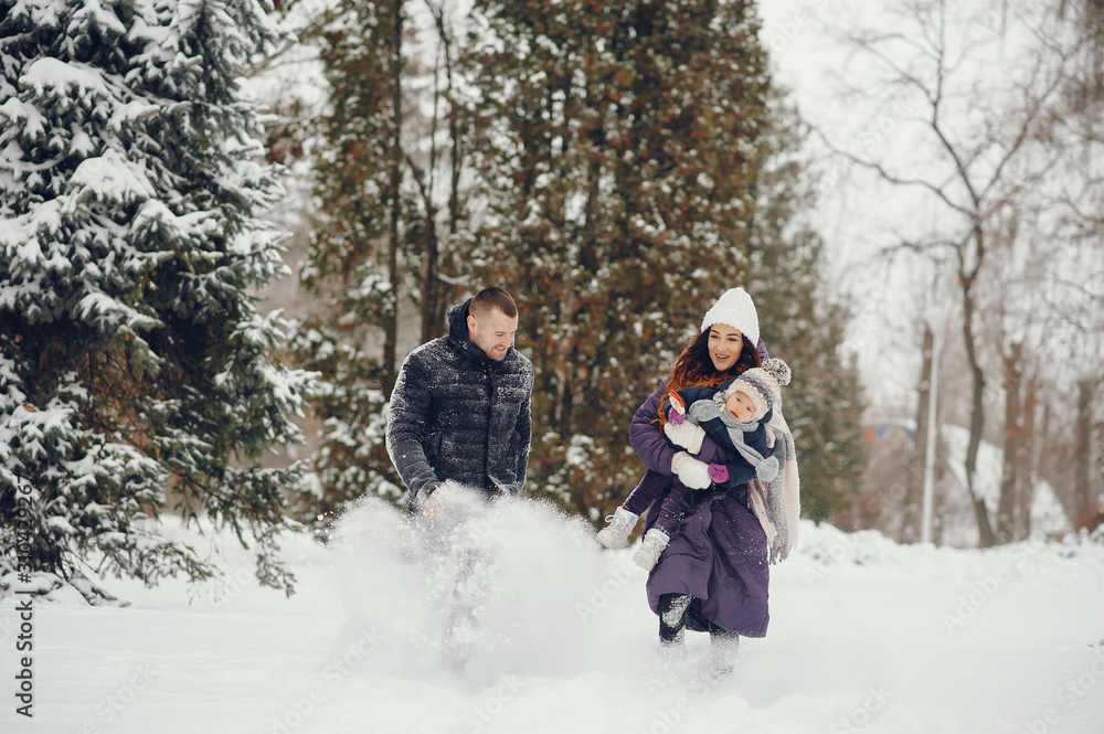 Family have fun in a winter park. Stylish mother in a purple jacket. Little girl in a winter clothes. Father with cute daughter