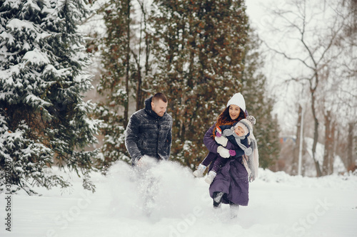 Family have fun in a winter park. Stylish mother in a purple jacket. Little girl in a winter clothes. Father with cute daughter