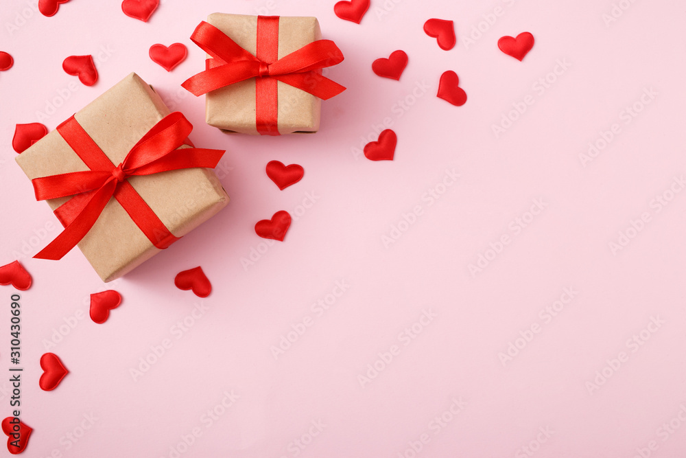 Presents with red bow on pink background with heart confetti. Flat lay style. Valentine day concept Presents with red bow on pink background with heart confetti. Flat lay style. Valentine day concept
