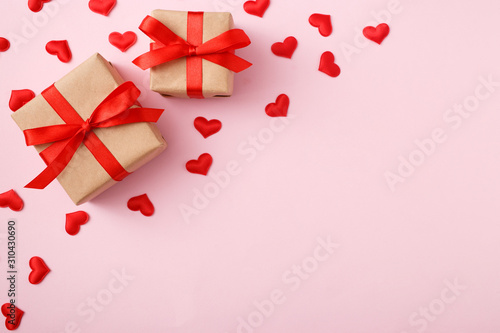 Presents with red bow on pink background with heart confetti. Flat lay style. Valentine day concept © KsPhoto