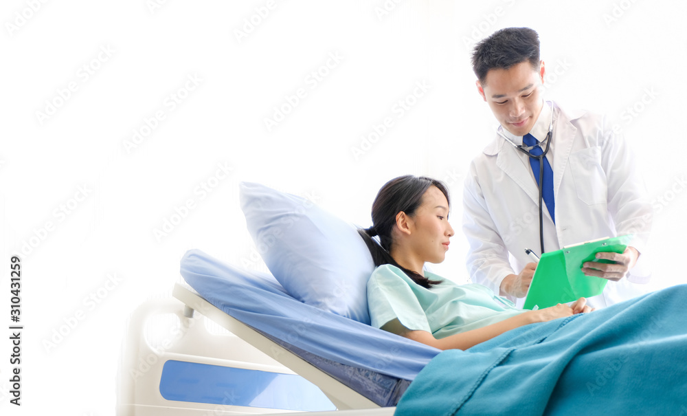 Obraz premium Asian Male doctor is talking to female patients lie in bed in the hospital room about the diagnosis of her illness.disease treatment and health care concept