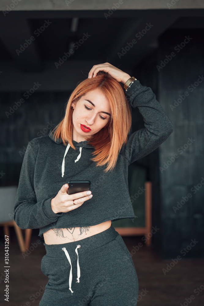Fototapeta premium European white redhead woman hold smartphone indoor