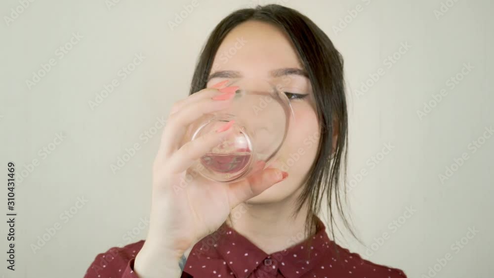 A young woman drinks water from a transparent glass. Close-up A young woman drinks water from a transparent glass. Close-up