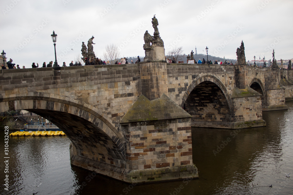  The main attraction of the Czech capital city of Prague is the Charles Bridge on Christmas Eve with many tourists and a view of the Vltava River.
